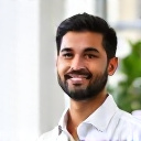 portrait of a happy latino businessman in his 40s wearing smart casual clothes, smiling confidently against a blurred office background